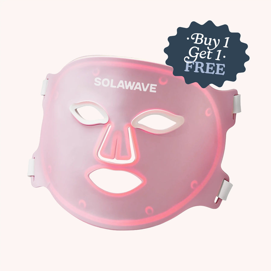 The Solawave Wrinkle Retreat Pro LED Face Mask with red, infrared, deep red, and amber light therapy is shown in pink with cutouts for the eyes, nose, and mouth. A "Buy 1 Get 1 Free" sticker appears on top right. White side straps complete the anti-aging design.